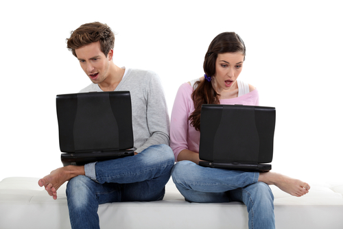 Couple on laptops in awe