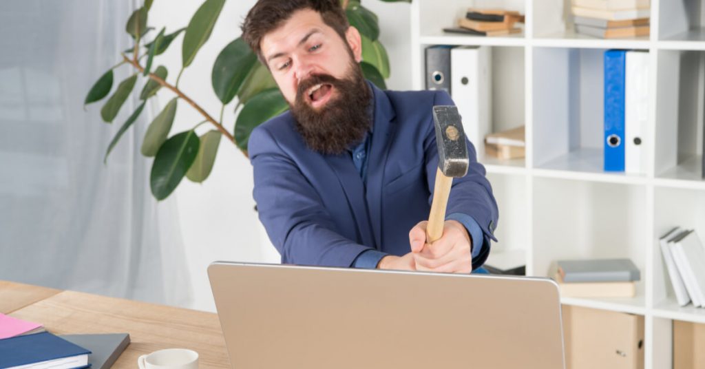 man smashing laptop with hammer